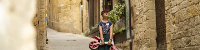 Child in the rue du Majou carrying a small bicycle