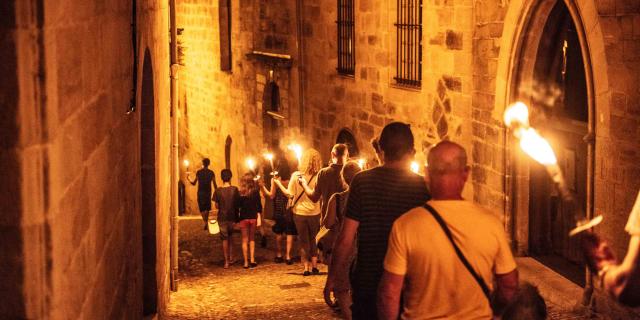 Une ruelle éclairée aux flambeaux d'une visite guidée à Figeac.