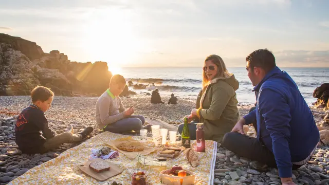 A family picnic on the pebbles of Le Lude harbour at sunset