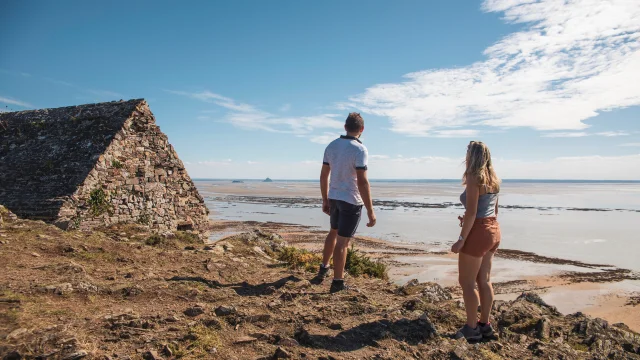 A couple observes Tombelaine and Mont saint-Michel from the Vauban hut on the Champeaux cliffs