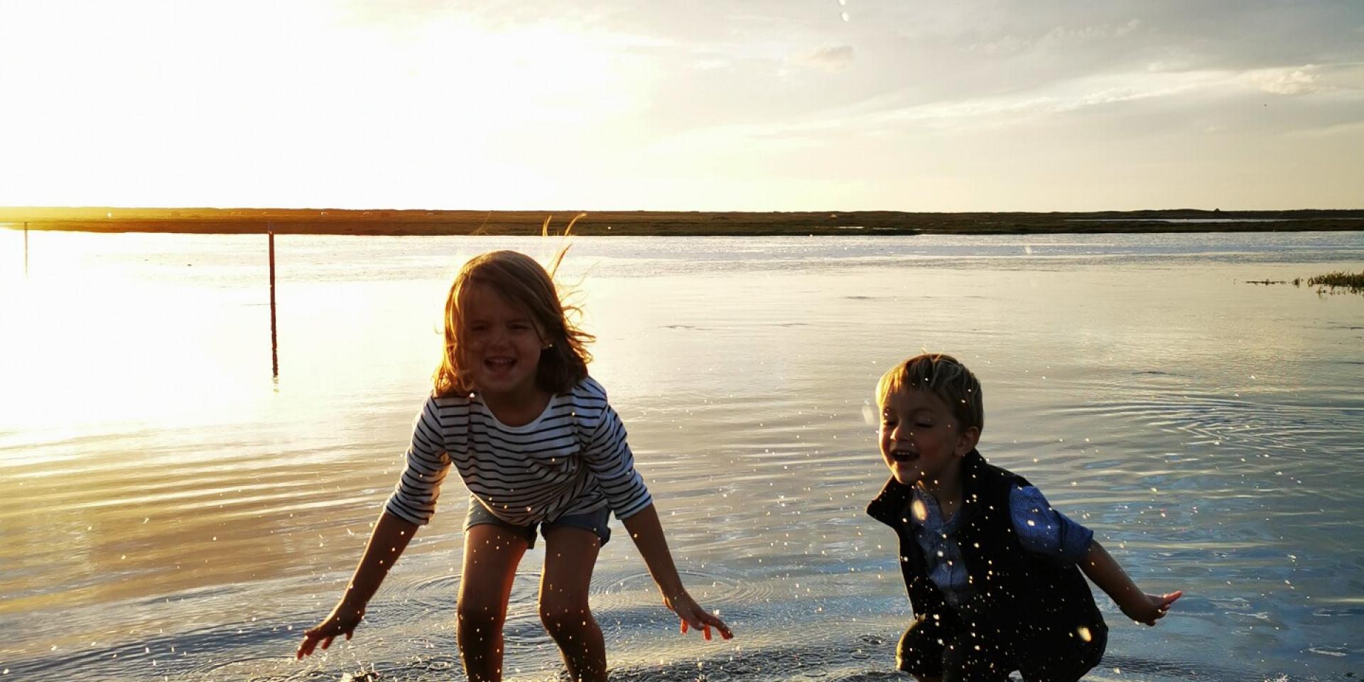 Children play with their feet in the water on the submersible road at Bricqueville-sur-Mer in the havre de la Vanlée during a high tide.