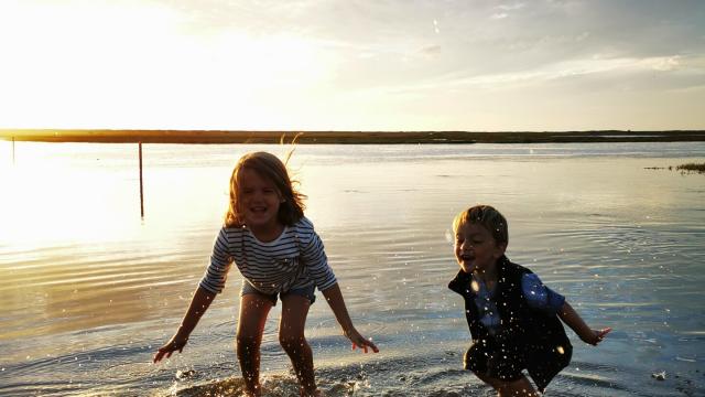 Children play with their feet in the water on the submersible road at Bricqueville-sur-Mer in the havre de la Vanlée during a high tide.