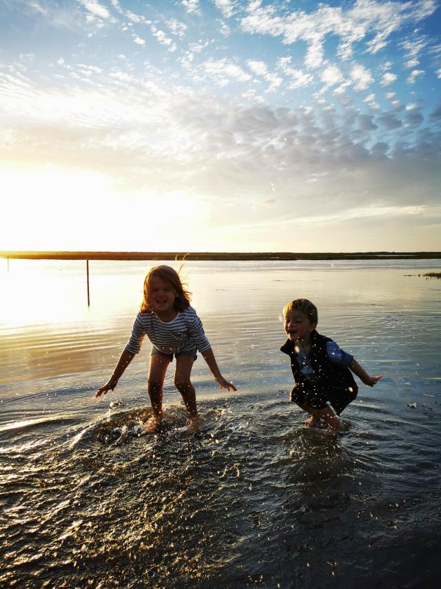 Children play with their feet in the water on the submersible road at Bricqueville-sur-Mer in the havre de la Vanlée during a high tide.