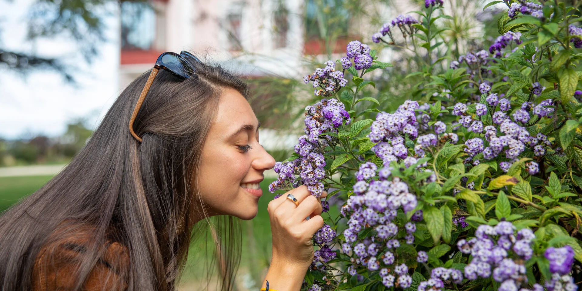 Une femme sent le parfum des fleurs dans le jardin du musée Christian Dior à Granville