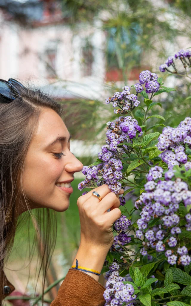 Une femme sent le parfum des fleurs dans le jardin du musée Christian Dior à Granville