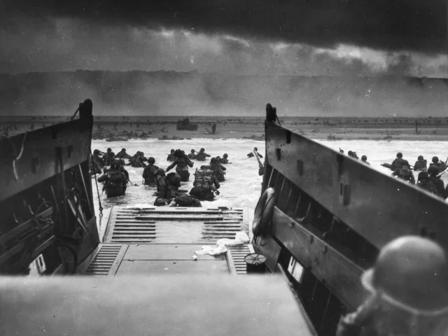 Army troops wade ashore on Omaha Beach during the D-Day landings, 6 June 1944. They were brought to the beach by a Coast Guard manned LCVP.  Photograph from the U.S. Coast Guard Collection in the U.S. National Archives.