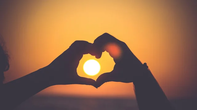 Cœur avec les mains face au coucher de soleil