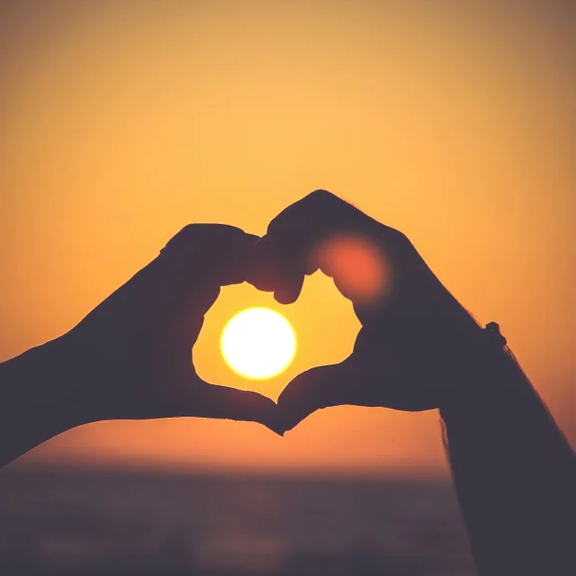 Cœur avec les mains face au coucher de soleil