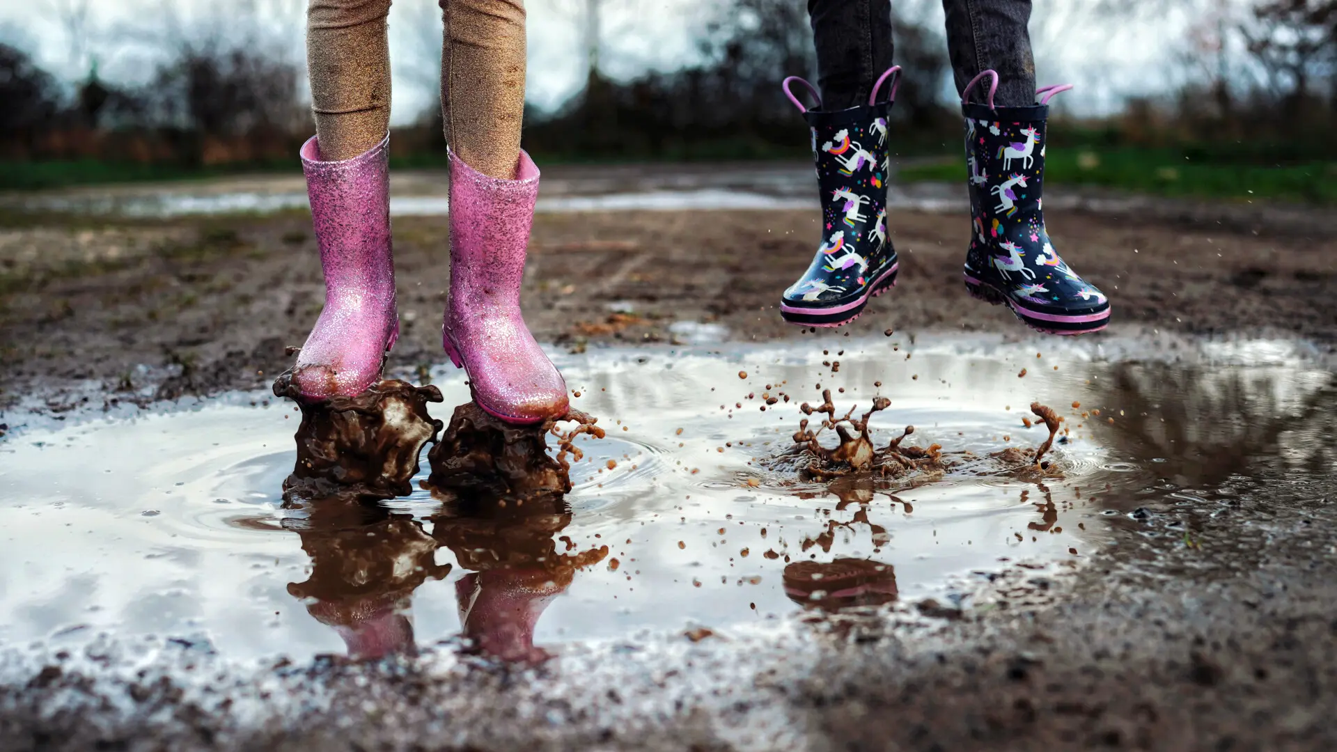 Des enfants en bottes sautent dans une flaque d'eau