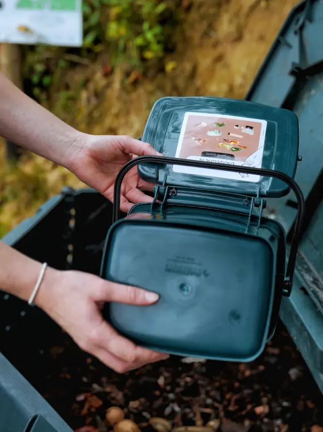 Une femme verse ses déchets alimentaires dans un bac à compost chez O2 Camping