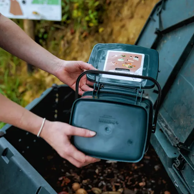 Une femme verse ses déchets alimentaires dans un bac à compost chez O2 Camping