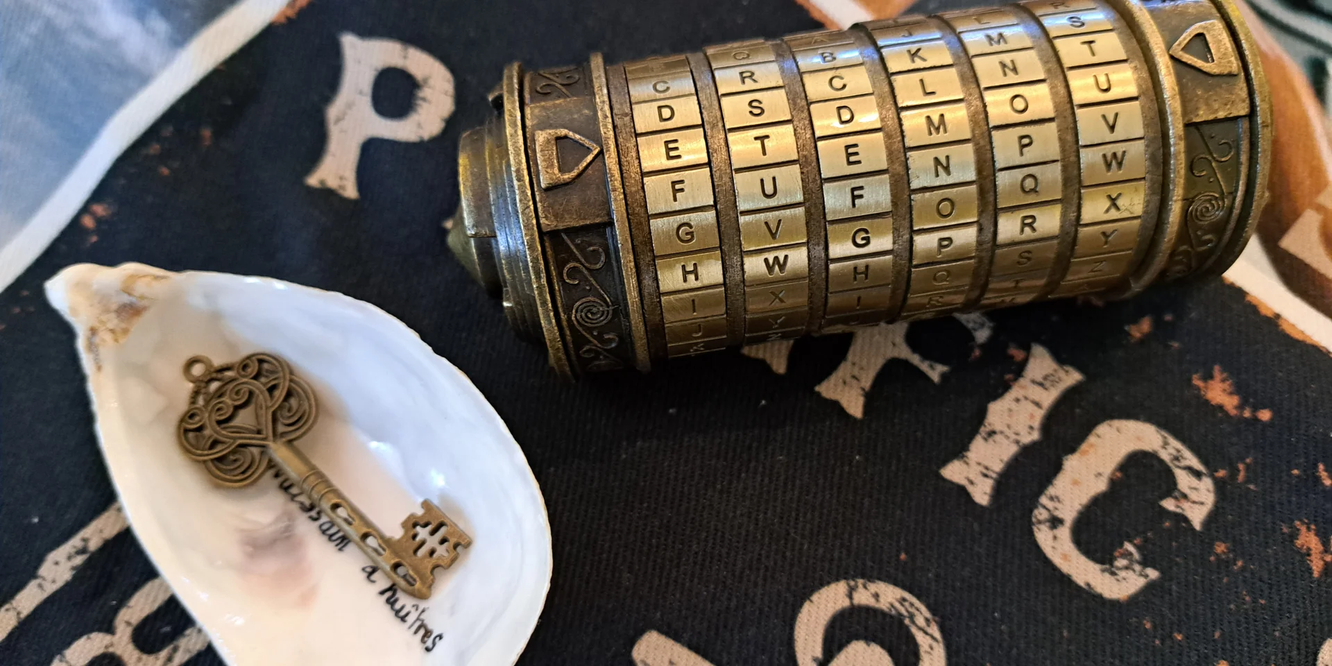 Cryptex pour déchiffrer un code avec des lettres. Sur la gauche une clef dans un coquille d'huître
