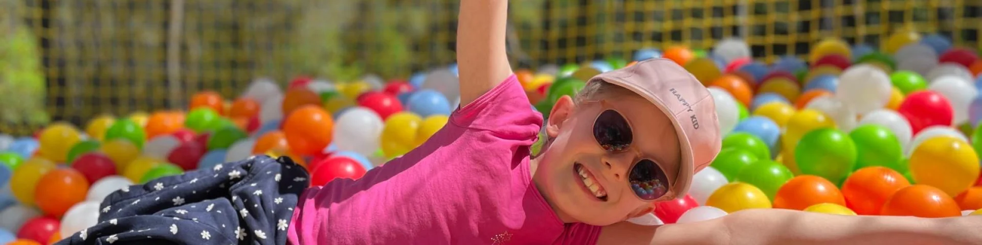 Enfant jouant dans une piscine de boules de couleurs, perché dans les arbres, faisant partie du parc de loisirs la cité perchée