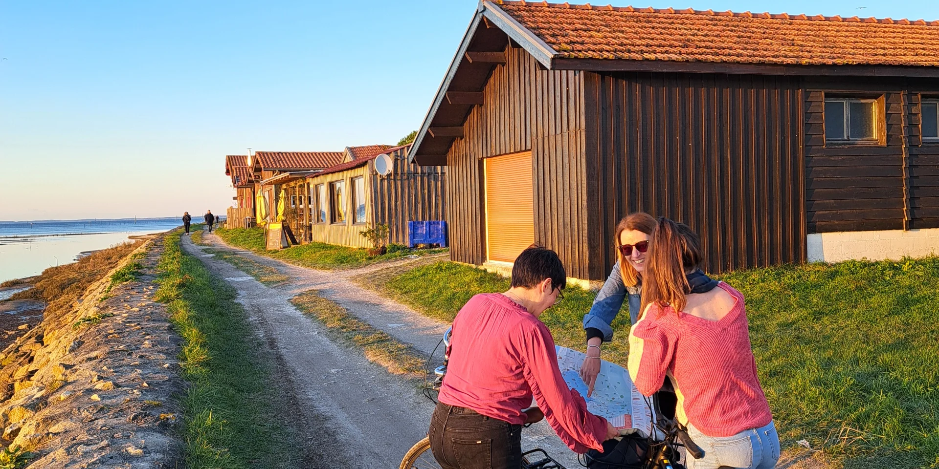 Des touristes à vélo sur le port de Larros qui sont en train de regarder la carte des déplacements pour connaître leur itinéraire
