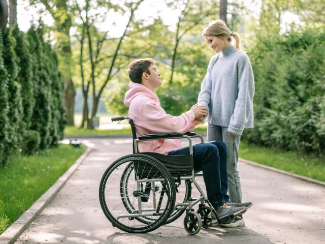 2 personnes parlant et se serrant la main dont une est en fauteuil roulant