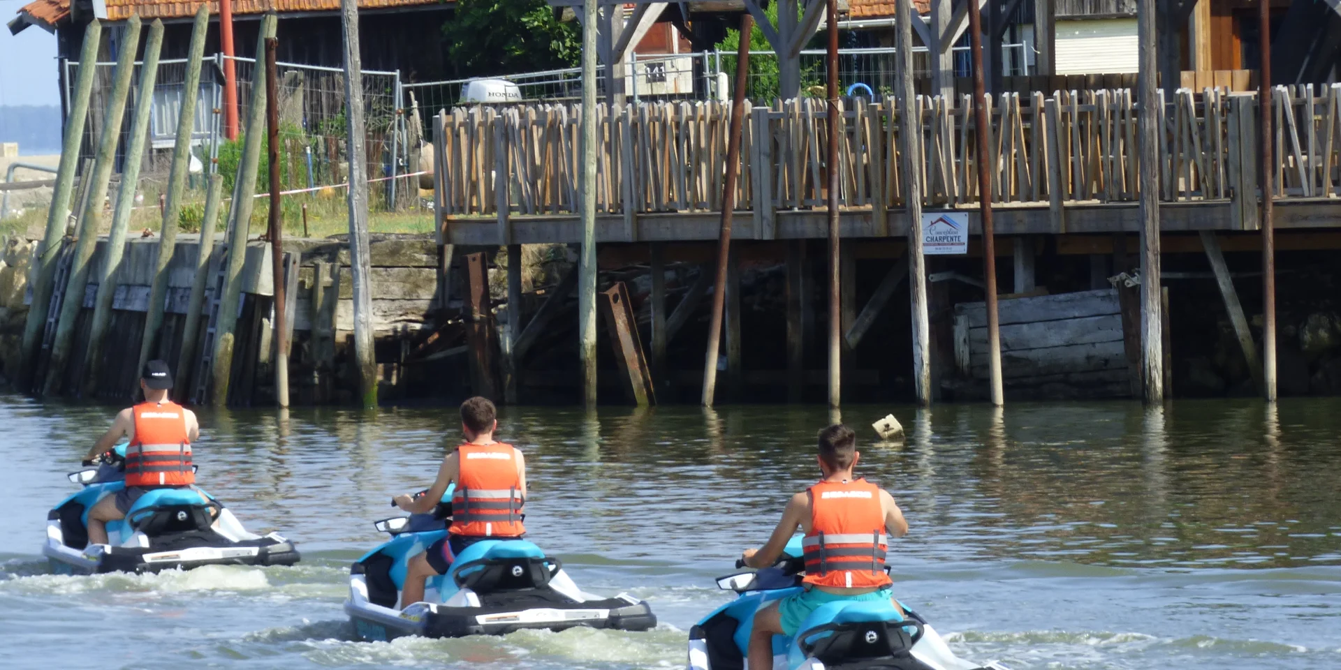 3 personnes de dos chacune sur un jet ski en train de quitter le port de Larros
