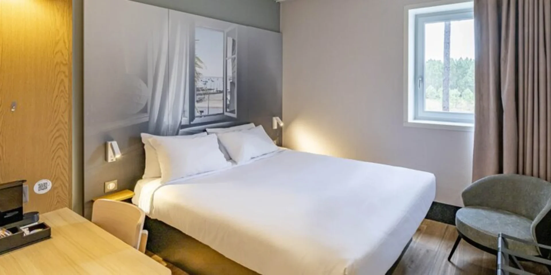 lit pour 2 personnes dans un hôtel avec une fenêtre ouverte au dessus du lit et un bureau à gauche de la photo