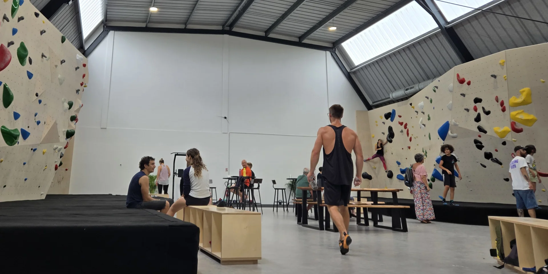 Salle d'escalade avec deux murs grimpes et des personnes se préparant à monter.