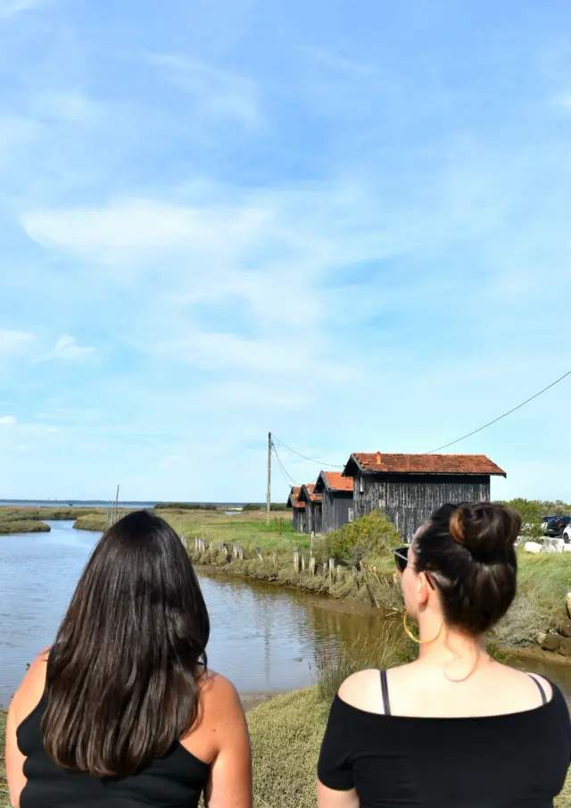 Deux femmes qui discutent assise sur un muret devant le Bassin au Port de la Mole à Gujan-Mestras