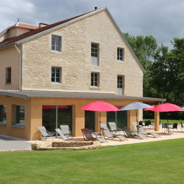 Vue extérieure du Gîte de la Tourelle à Bay, avec la terrasse aménagée de bains de soleil et de parasols - Vallée de l'Ognon