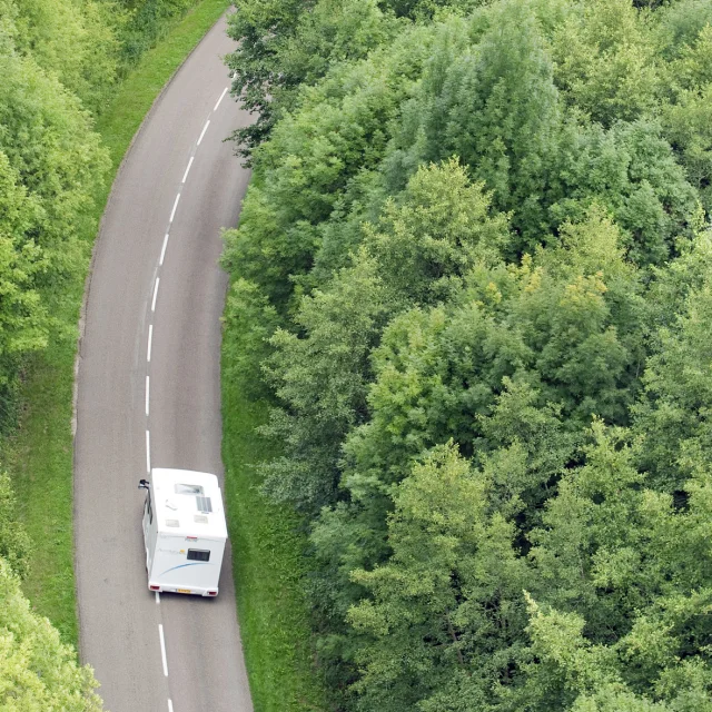 Un camping-car sillonne la route au milieu de la forêt