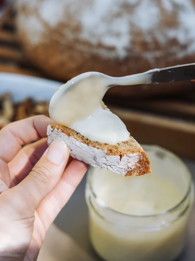 Une femme étale de la cancoillotte IGP sur un morceau de pain, cancoillotte fabriquée par la fromagerie bio La Fleurizelle à Aboncourt-Gesincourt - Vesoul-Val de Saône