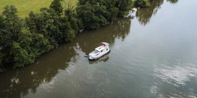 Vue aérienne d'un bateau sans permis navigant sur la Saône, dans un cadre de nature préservée, au milieu de la verdure - Vesoul-Val de Saône