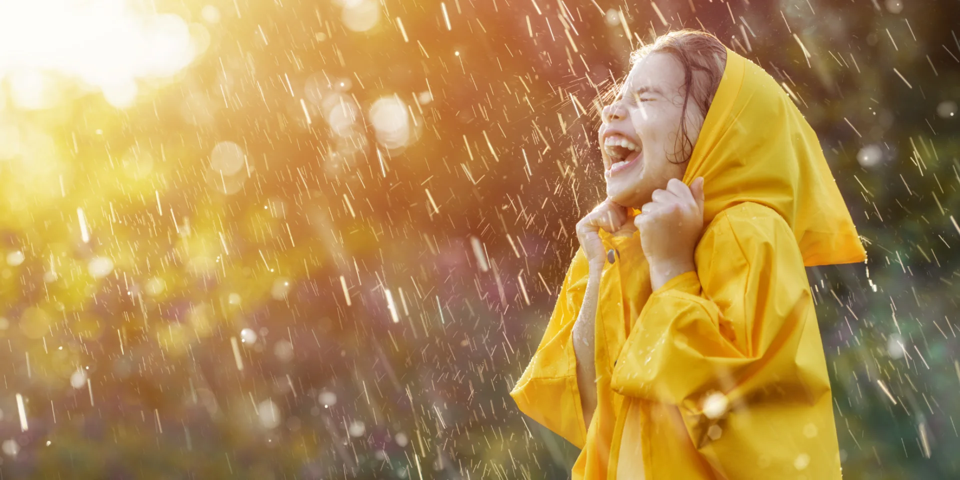 Une petite fille en ciré jaune rit sous la pluie