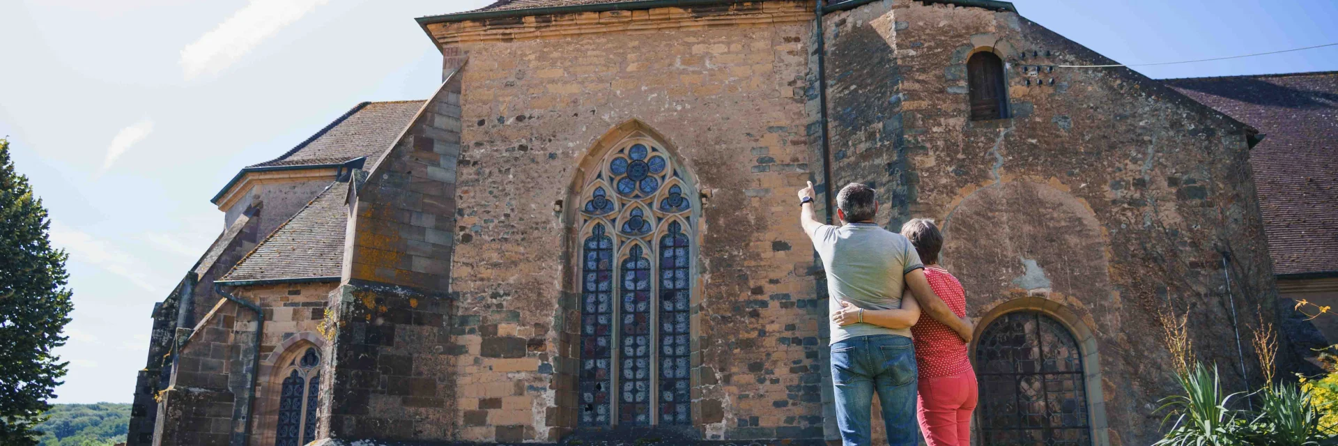 Un couple regarde l'église abbatiale de Faverney. L'homme pointe du doigt le clocher - Vesoul - Val de Saône