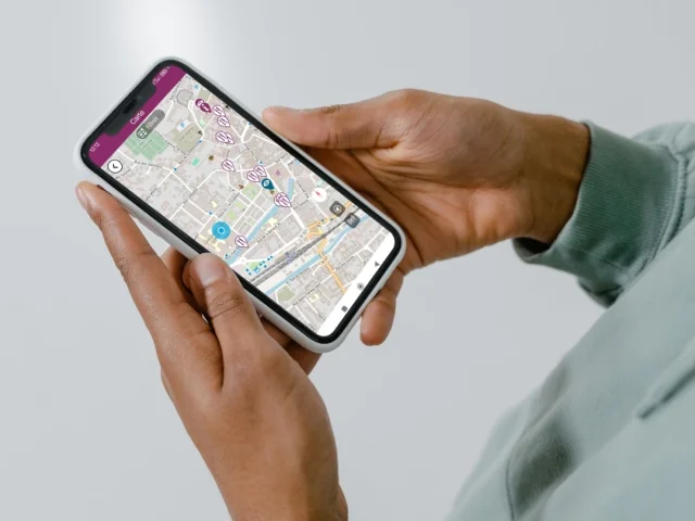Une personne tient un smartphone avec l'application My Haute-Saône ouverte, permettant de voir les points d’intérêt à proximité sur une carte de situation - Haute-Saône