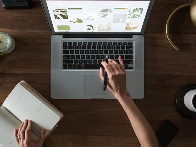 Une femme travaille sur un PC et prend des notes sur un carnet - Audit d'outils digitaux par Destination 70
