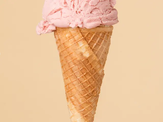 cornet ice cream with a strawberry scoop on a colorful background