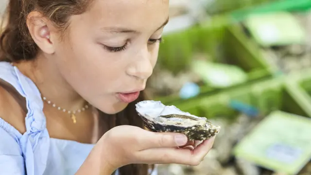 Petite fille avec une huître dans ses mains au marché de La Baule