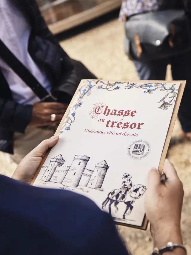 Mains qui tiennent un support de visite pour faire une chasse au trésor à Guérande