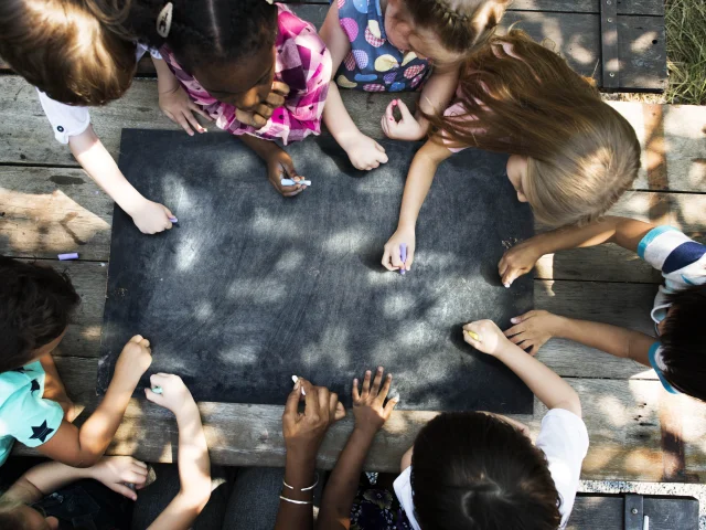 Groupe D Enfants dessinant sur un tableau en ardoise posé sur une table