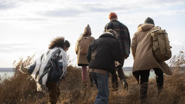 Plusieurs amis marchent ensemble en bord de mer en hiver