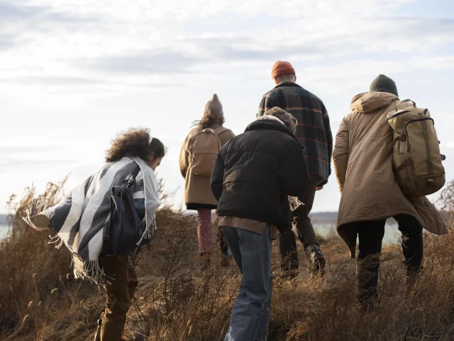Plusieurs amis marchent ensemble en bord de mer en hiver