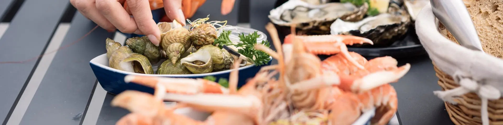 mainq ui se sert des langoustines et des huîtres, présentés sur une table