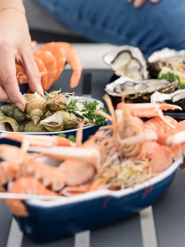 mainq ui se sert des langoustines et des huîtres, présentés sur une table