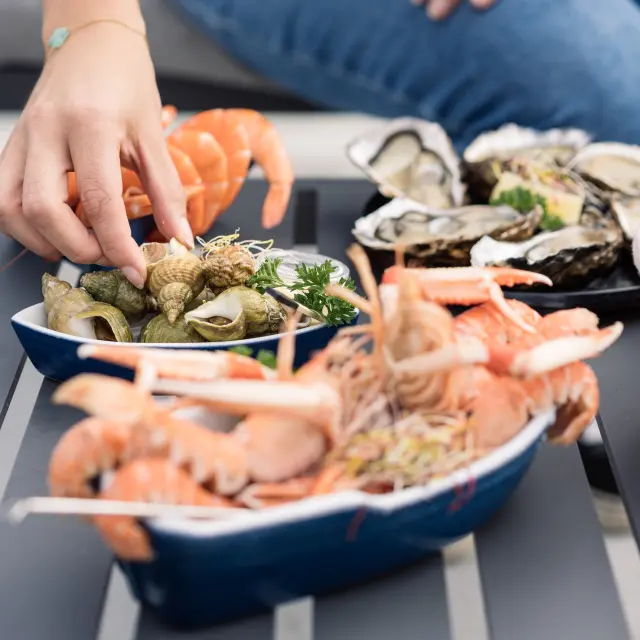 mainq ui se sert des langoustines et des huîtres, présentés sur une table