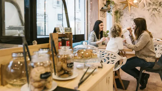 Des amies et une petite fille porfite de douceurs dans un salon de thé