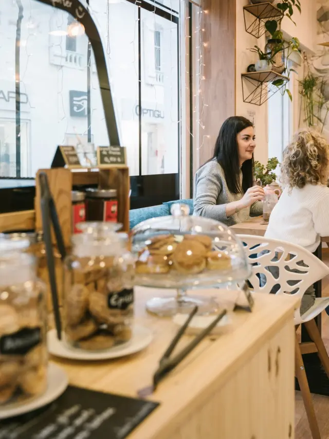 Des amies et une petite fille porfite de douceurs dans un salon de thé