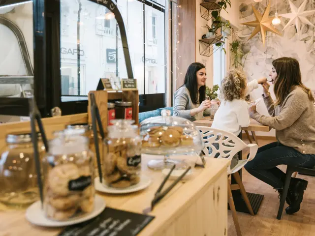 Freundinnen und ein kleines Mädchen, das in einer Teestube Süßigkeiten genießt