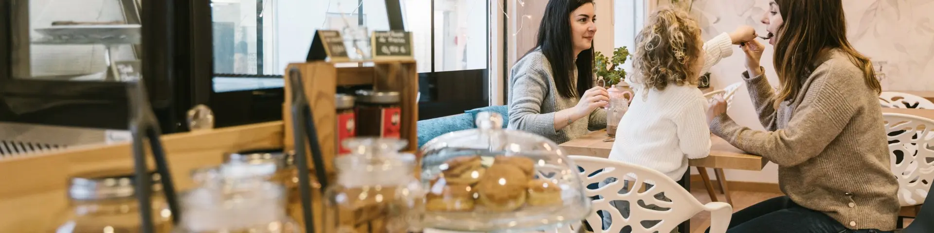 Des amies et une petite fille porfite de douceurs dans un salon de thé