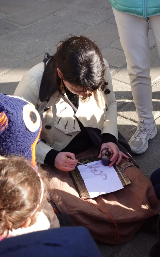 Enfants qui entourent une guide. Ils qui participent à une visite guidée intitulée Chasse au dragon à Guérande