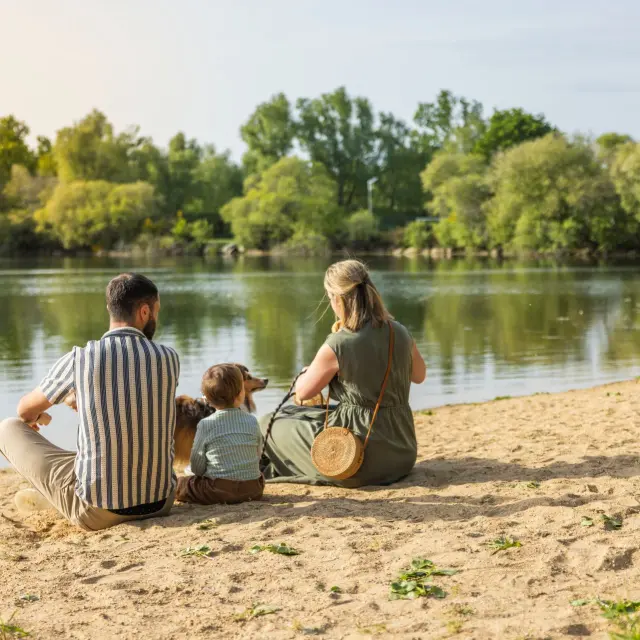 Famille assise sur la petite plage de la base de loisirs de Saint-Lyphard