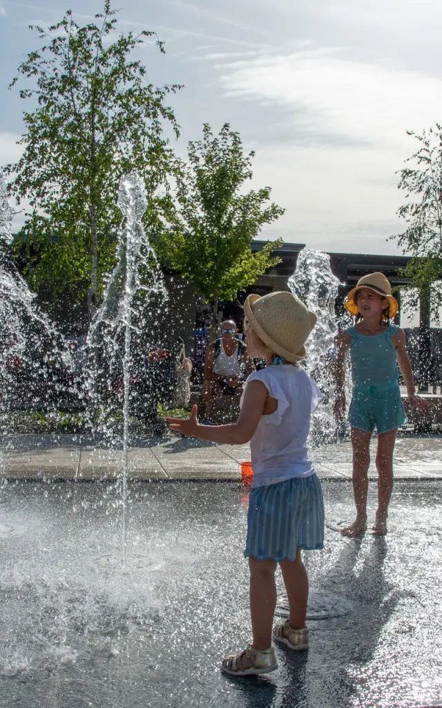 Jeune femmes avec des enfants en train de jouer dans une fontaine à eau