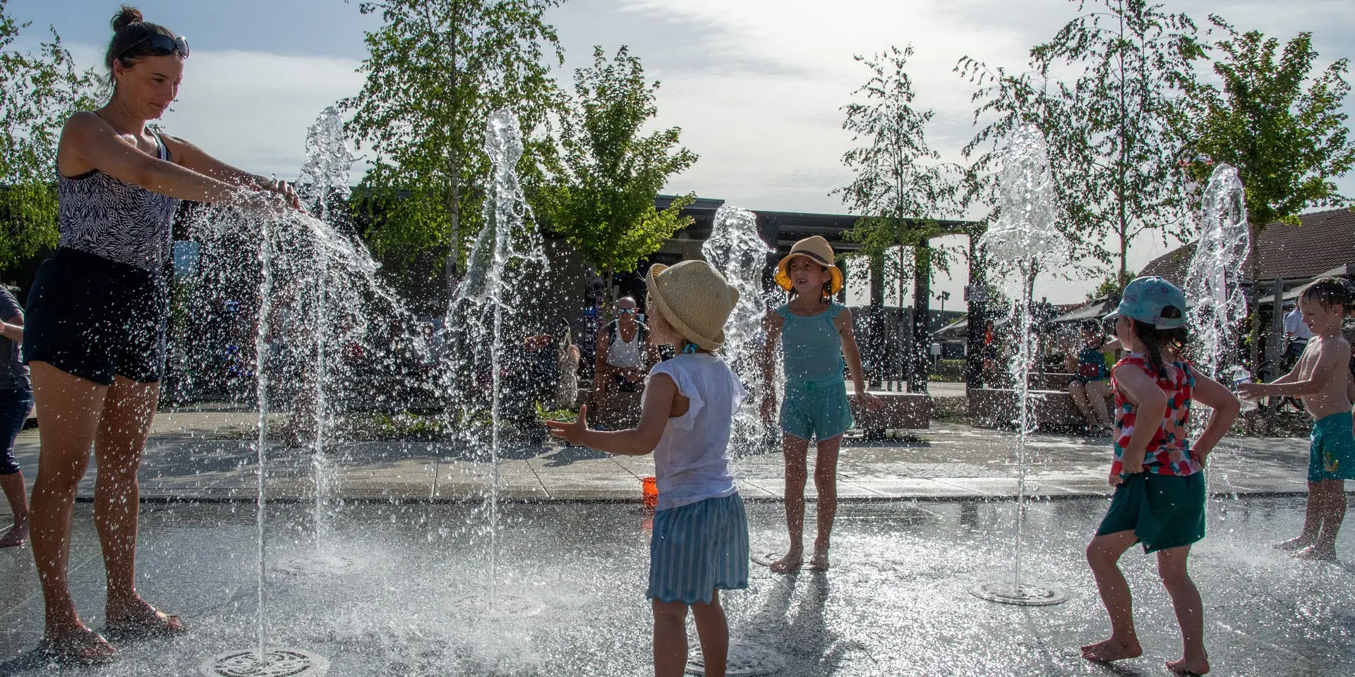 Jeune femmes avec des enfants en train de jouer dans une fontaine à eau
