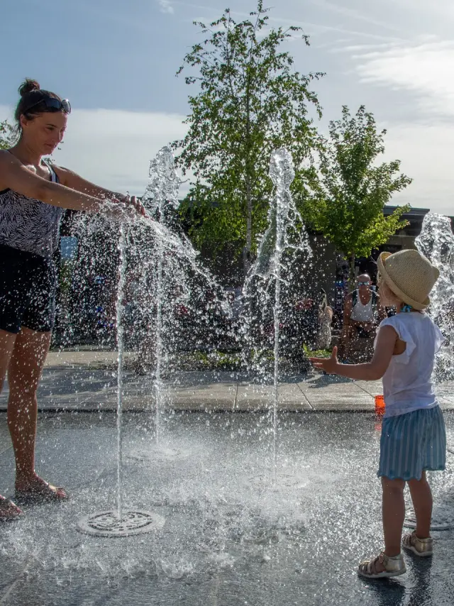Jeune femmes avec des enfants en train de jouer dans une fontaine à eau