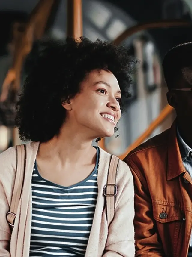 A happy African-American couple looking out of the window whilst travelling together by bus.